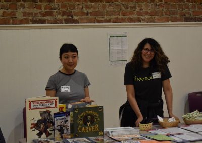 Volunteers at a information table with books and resources.